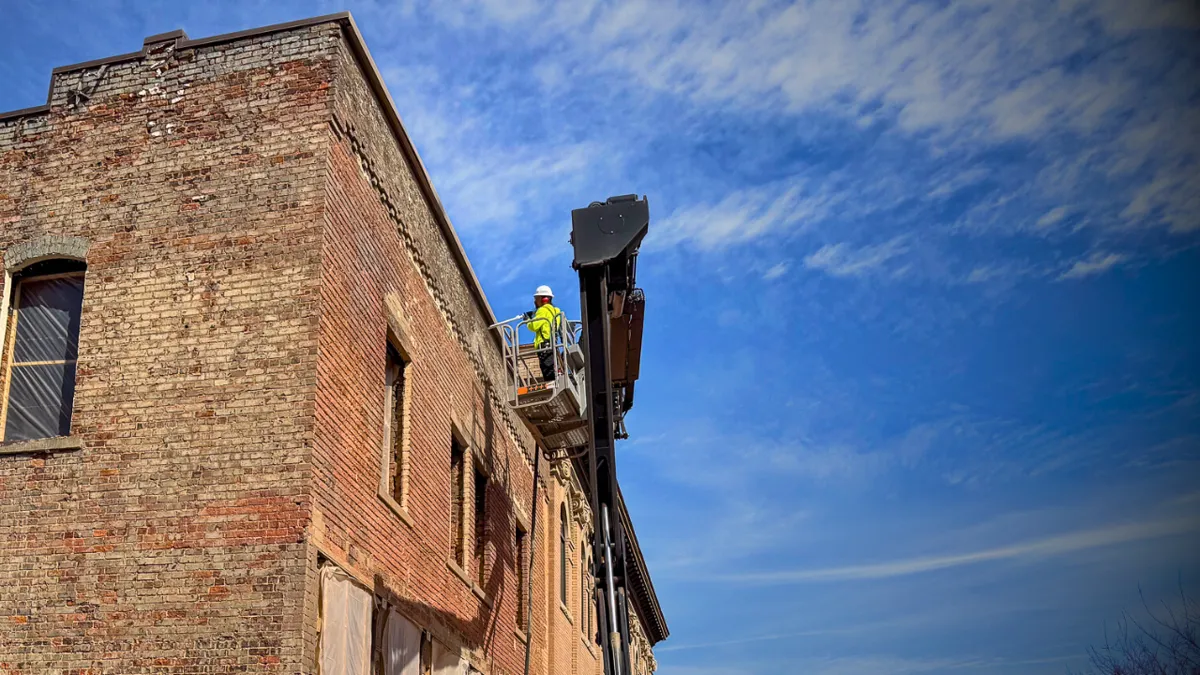 Worker on a boom lift restoring a commercial brick building facade